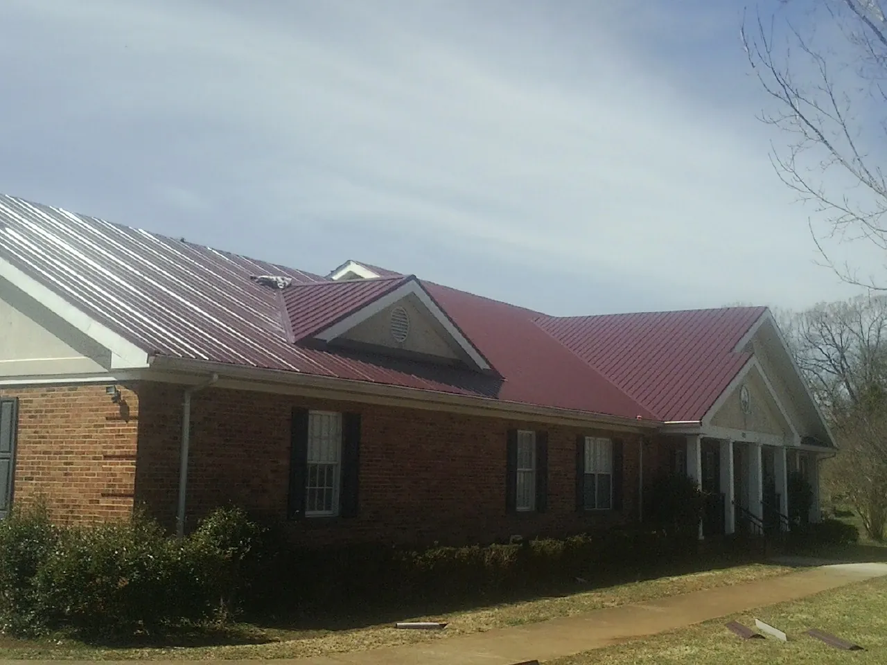 Red metal roof with gabled entries on a long brick building in Center Cross