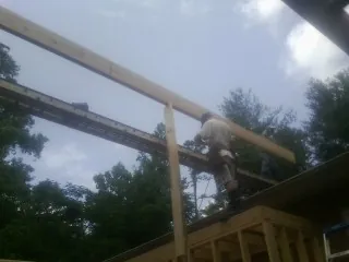 Carpenter setting a ridge beam over a new addition frame — Ice Dam Removal by Roofing Brothers in Center Cross