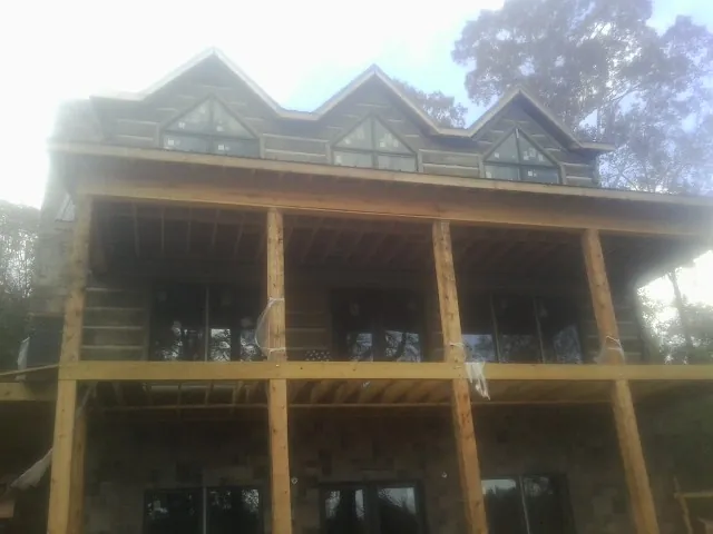 Dormers and porch framing on a large log home under construction — Roof Coating work by our crew in Center Cross