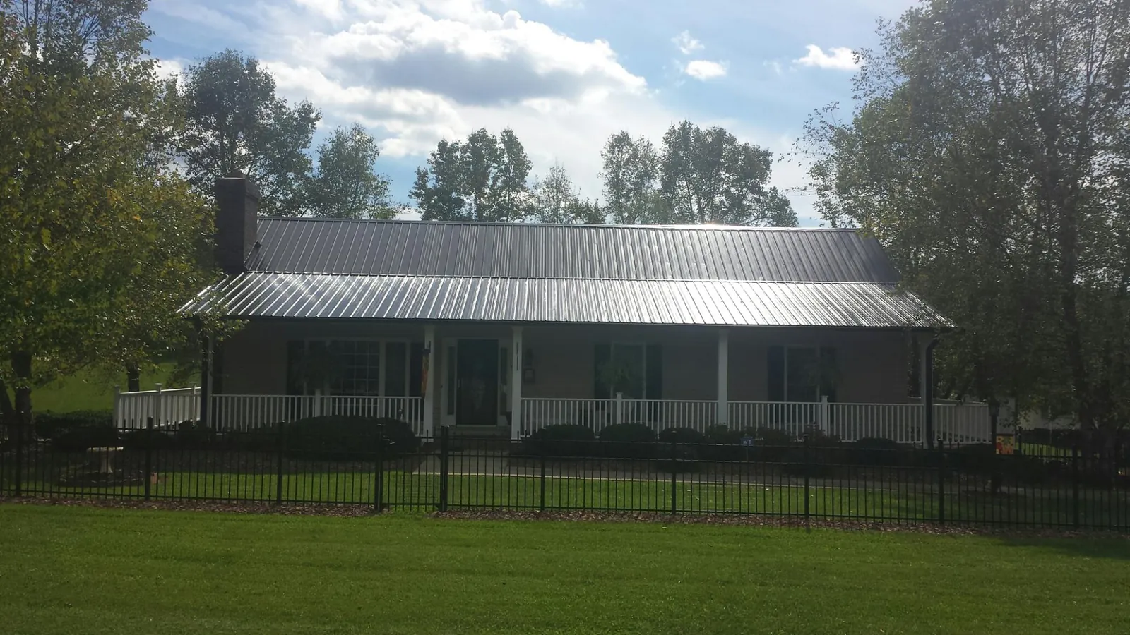 Gray metal roof on a brick ranch with a full width front porch — Gutter Guard Installation work by our crew in Center Cross
